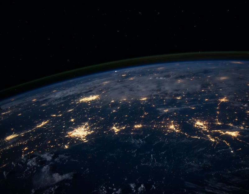 Picture of a dark earth with different lights on the surface taken from outer space