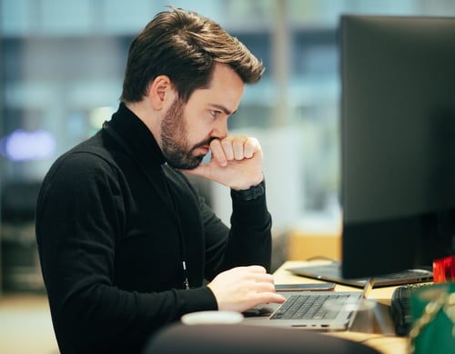 Portrett av en mann som sitter foran en PC og ser konsentrert ut