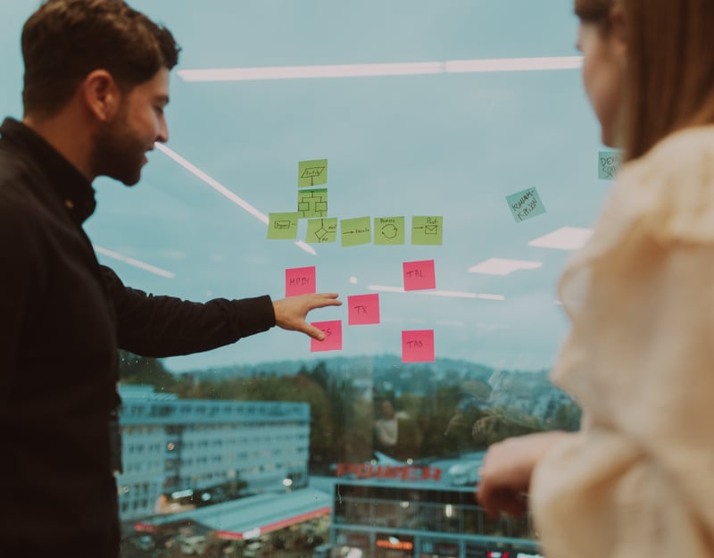 Man and woman are putting post-it notes on a window