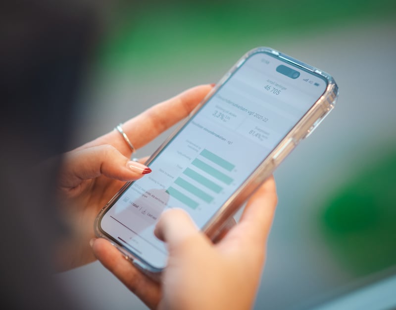 Close up picture of someone writing on a phone with graphs on