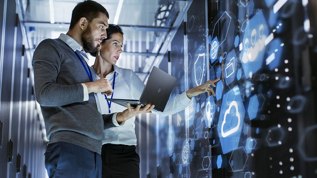 A woman and a man are looking at different data sources.